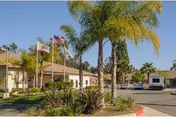 Exterior view of Trabuco Hills Post-Acute with flags, palm trees, and a driveway.