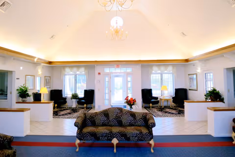 Bright vaulted-ceiling lobby seating area with sofas, armchairs, chandeliers and a central glass entrance.