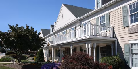 Exterior view of a senior living building with a covered porch and balcony.