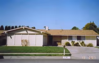 Exterior view of a single-story senior facility with a manicured lawn and driveway.