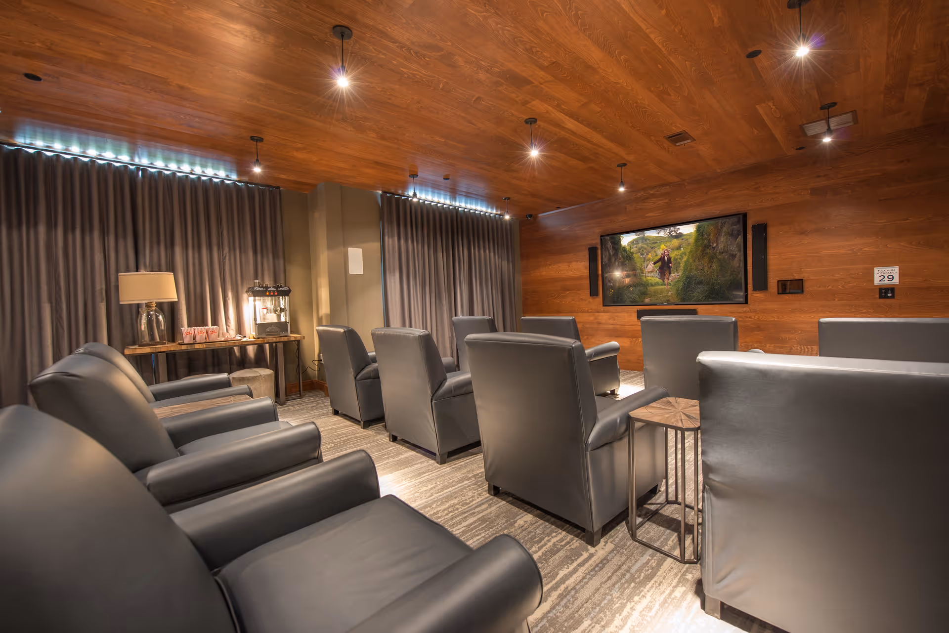 Cozy media room with rows of leather recliner chairs facing a wall-mounted TV in a wood-paneled room.