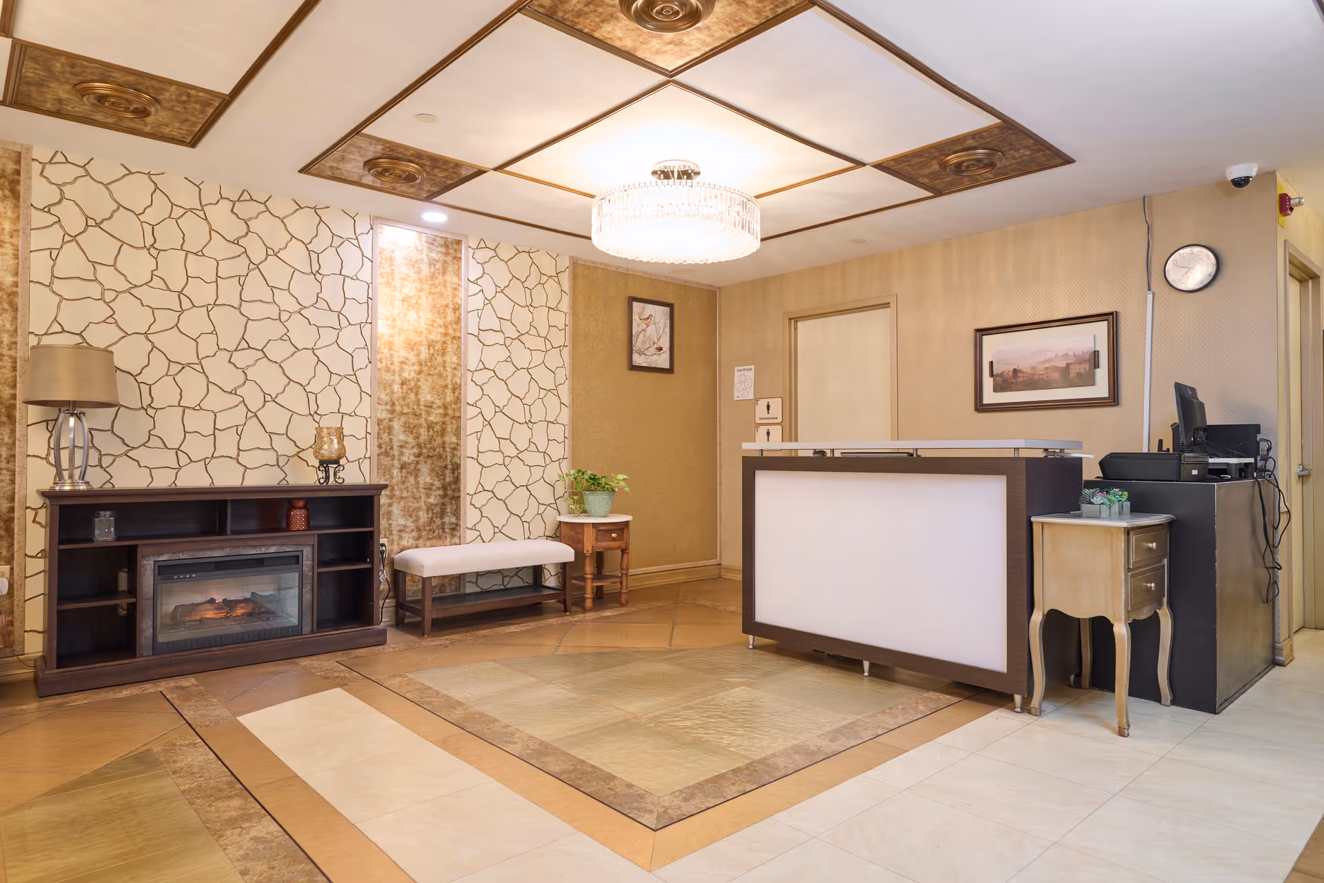 Reception lobby featuring a front desk, a bench, decorative wall panels, a chandelier, and a console with a fireplace.