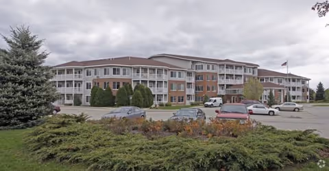 Exterior view of Howard Village Senior Living, a multi-story building with parked cars.