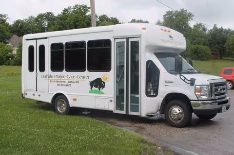 White Buffalo Prairie Care Center bus parked on a grassy area near the road.