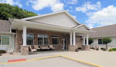 Front exterior of Elkader Care Center with brick facade and outdoor seating.