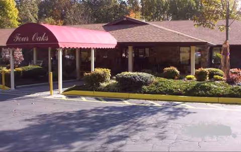 Facade of Four Oaks Healthcare Center with pink canopy, entryway, and manicured landscaping.