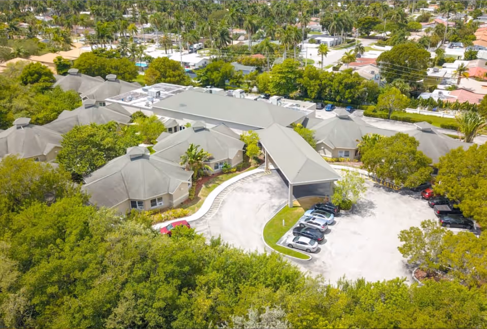 Aerial view of Majestic Memory Care facility with connected beige buildings, parking lot, and trees.