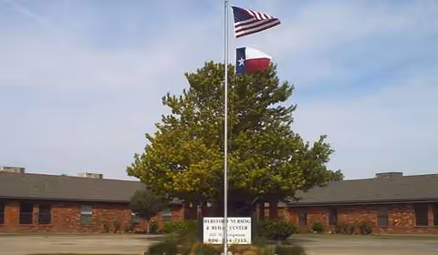 Front exterior of a brick senior living facility with flags