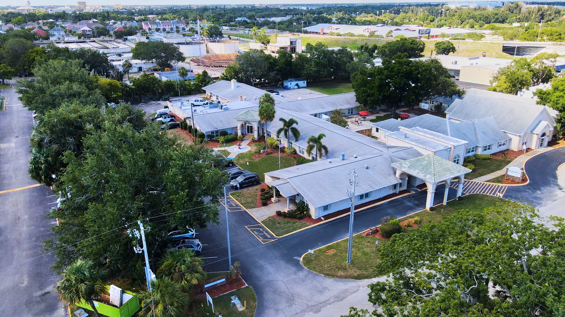 Aerial view of Greenbriar Rehabilitation and Nursing Center showing a single-story building complex with a covered entrance, surrounded by trees, parking areas, and nearby roads.