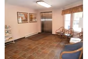 A small lobby area with an elevator, windows, chairs, and framed art.