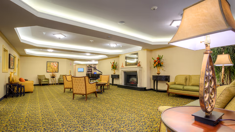 Spacious furnished common living area with chairs, sofas, lamps, a fireplace and a piano.