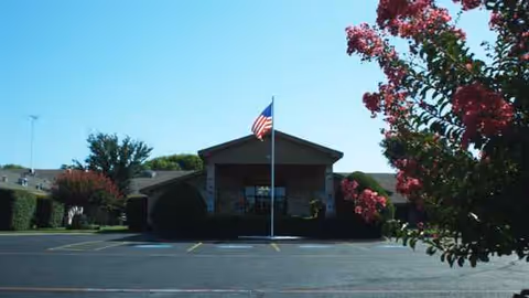 Front view of Lubbock Health Care Center building with American flag and parking lot.