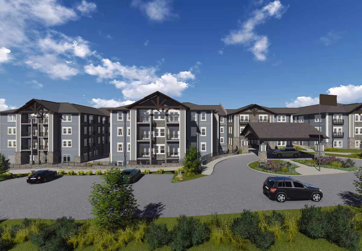 Exterior front view of a multi-story senior living building with a covered porte-cochère, landscaped driveway, and parked cars under a blue sky.
