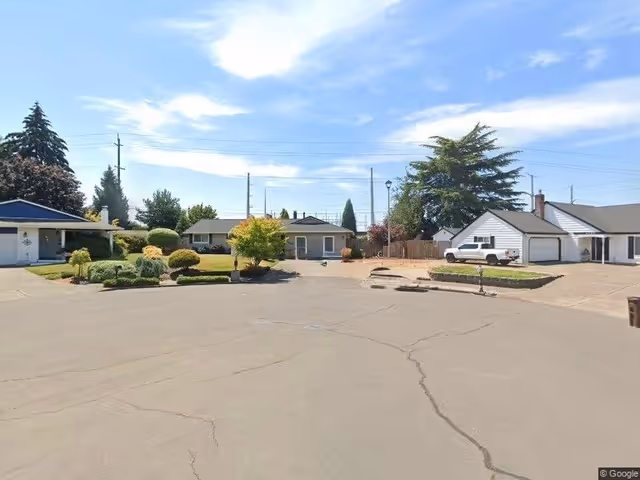 Exterior view of a senior living campus with driveways, landscaping, and parked vehicles.
