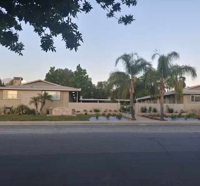 Front view of Rose Garden Residential Care building with palm trees along the street.