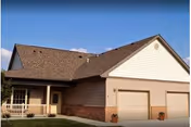 Front exterior of a single-story senior living building with a covered porch and two-car garage.