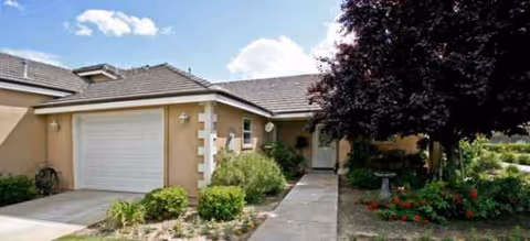 Front exterior of a single-story Riverwalk building with a garage, walkway, and landscaping.