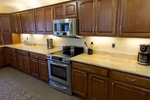 Long kitchen with wooden cabinets, stainless steel appliances, and a coffee maker.