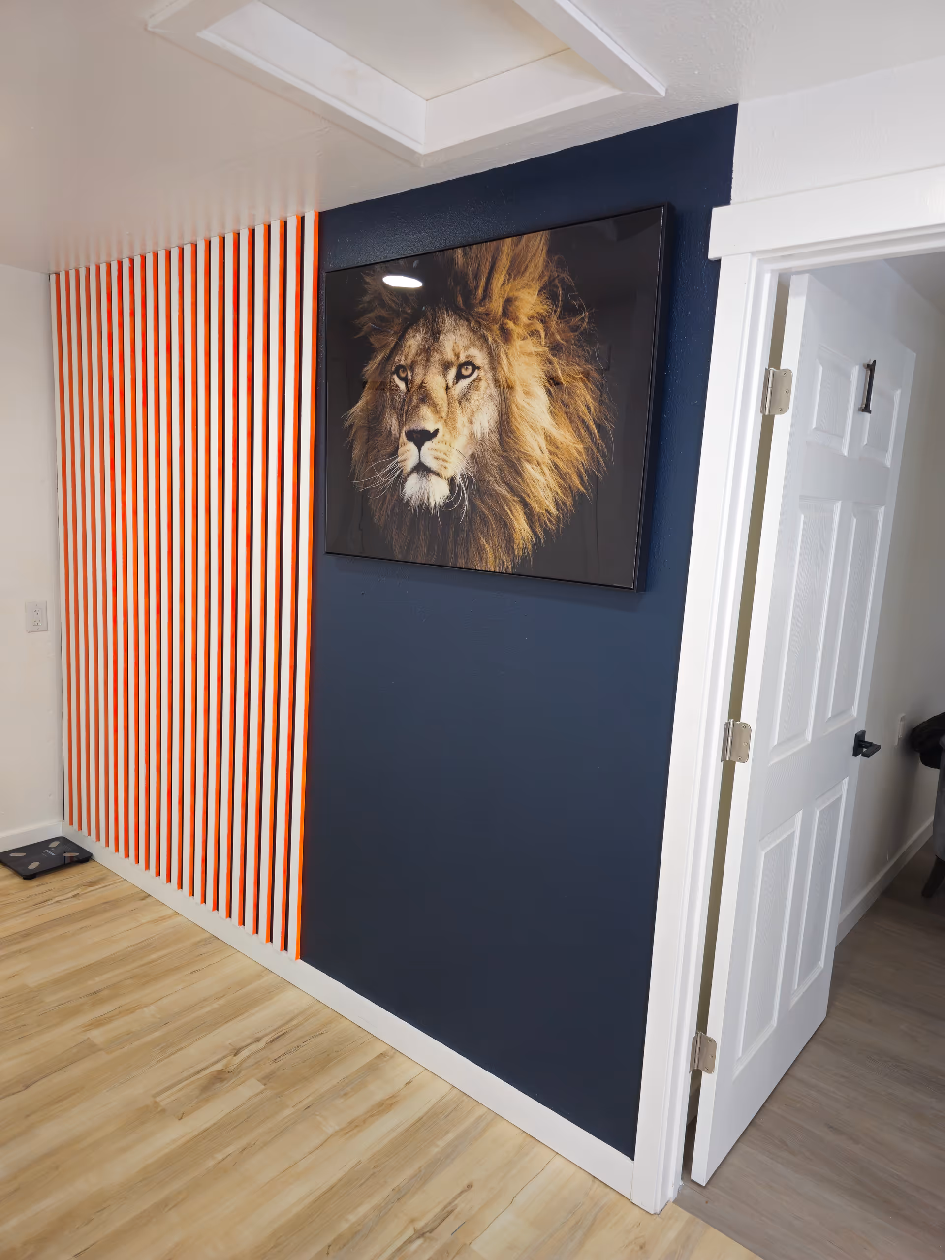 A corner of a room featuring a lion portrait on a wall with striped decoration.