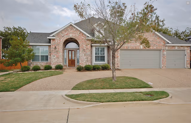 Brick single-story home with a two-car garage and manicured lawn along the curb.