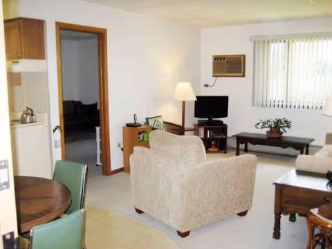 Cozy living room in Highland Oaks with sofa, coffee table, TV, and window blinds.