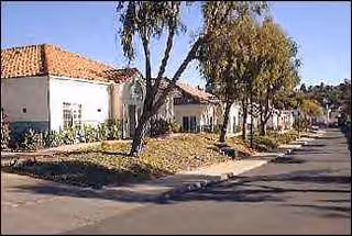 Exterior view of a single-story senior care facility with trees along a street.