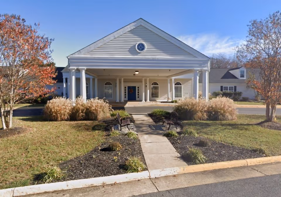 Front view of Cambridge Landing Memory Care building with columns and landscaped entrance