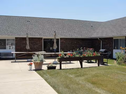 Outdoor courtyard of a brick senior living facility with planters and seating.