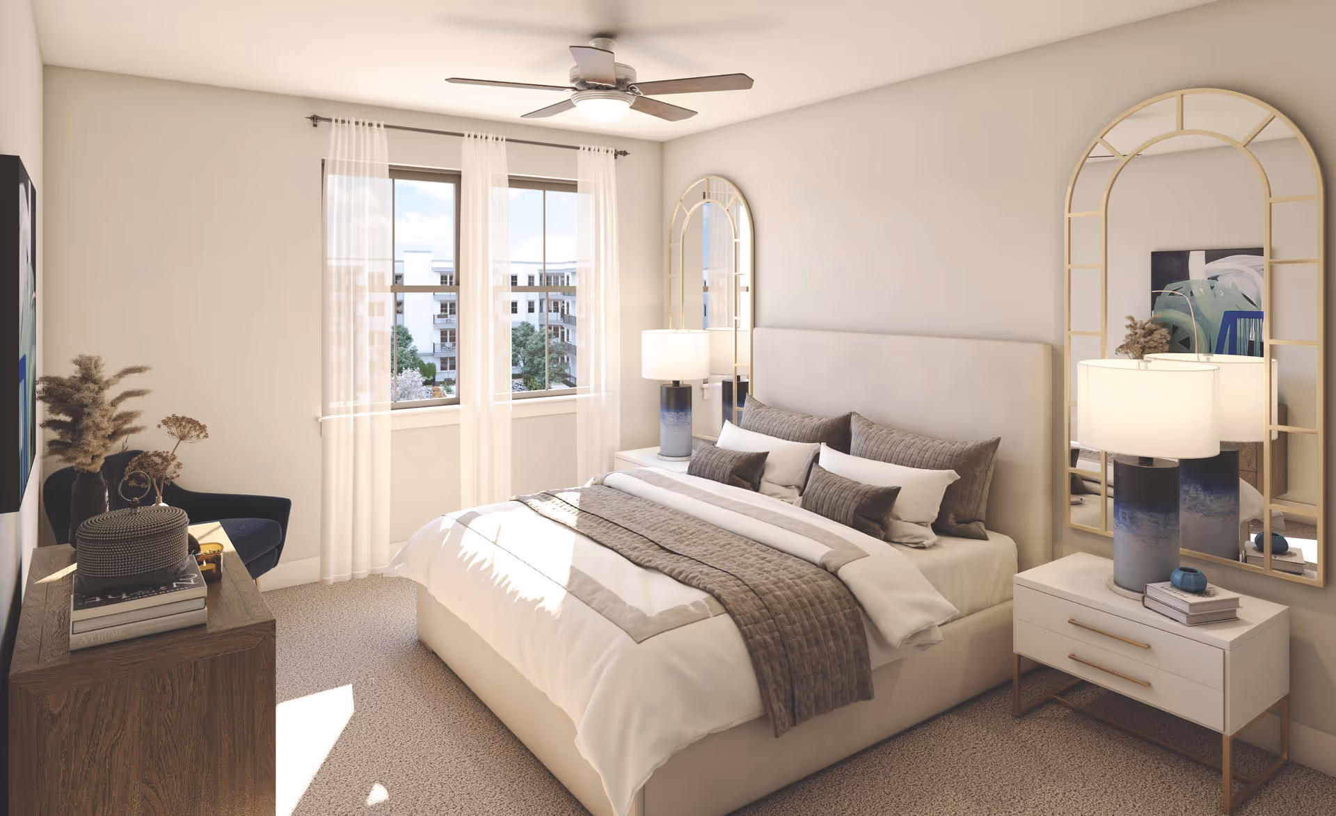 Bright, furnished bedroom with a large bed, bedside tables and lamps, decorative mirrors, a dresser and a window with sheer curtains.