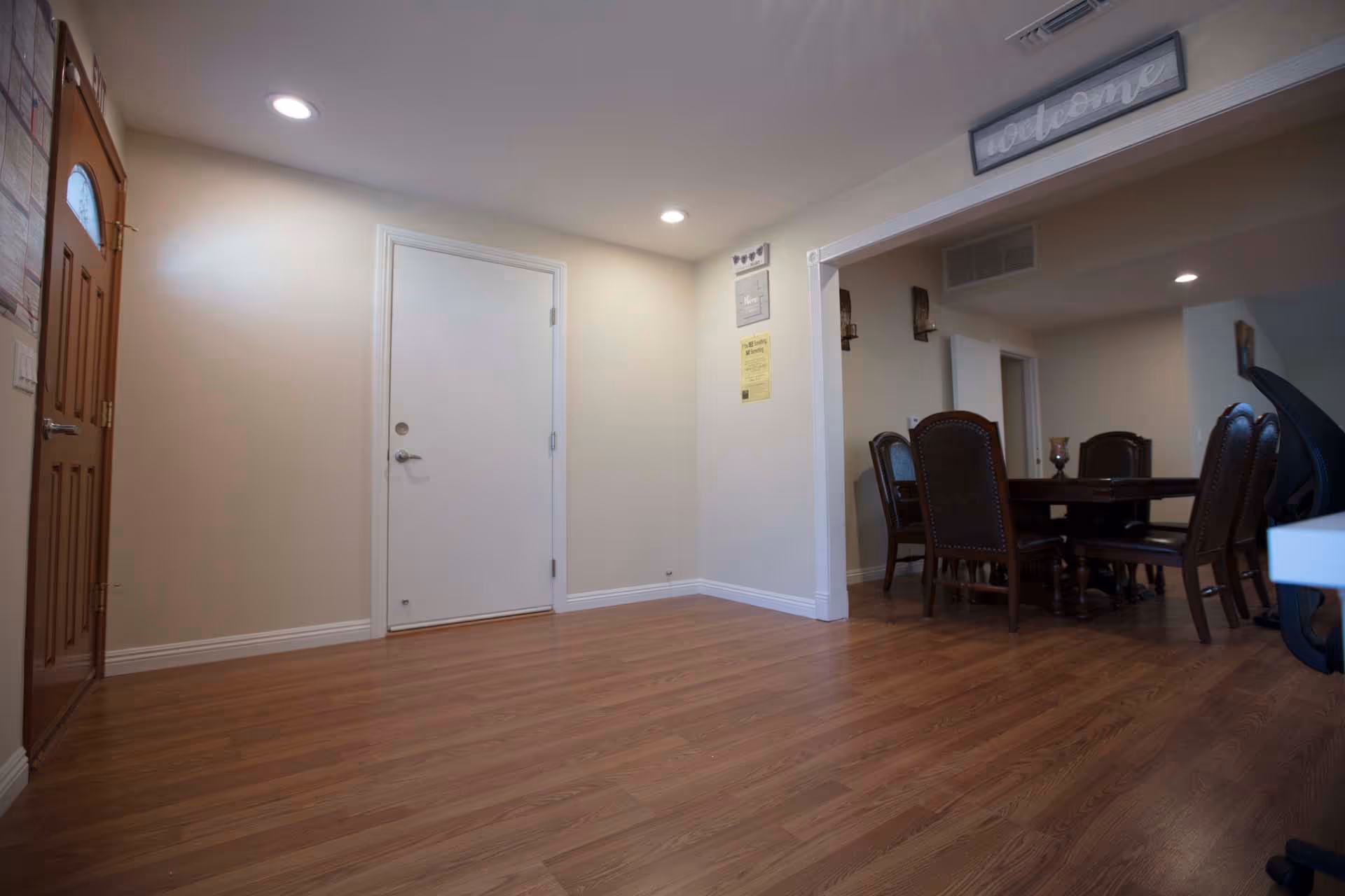 Foyer with wood flooring and recessed lighting opening into a dining area with a wooden table and chairs.
