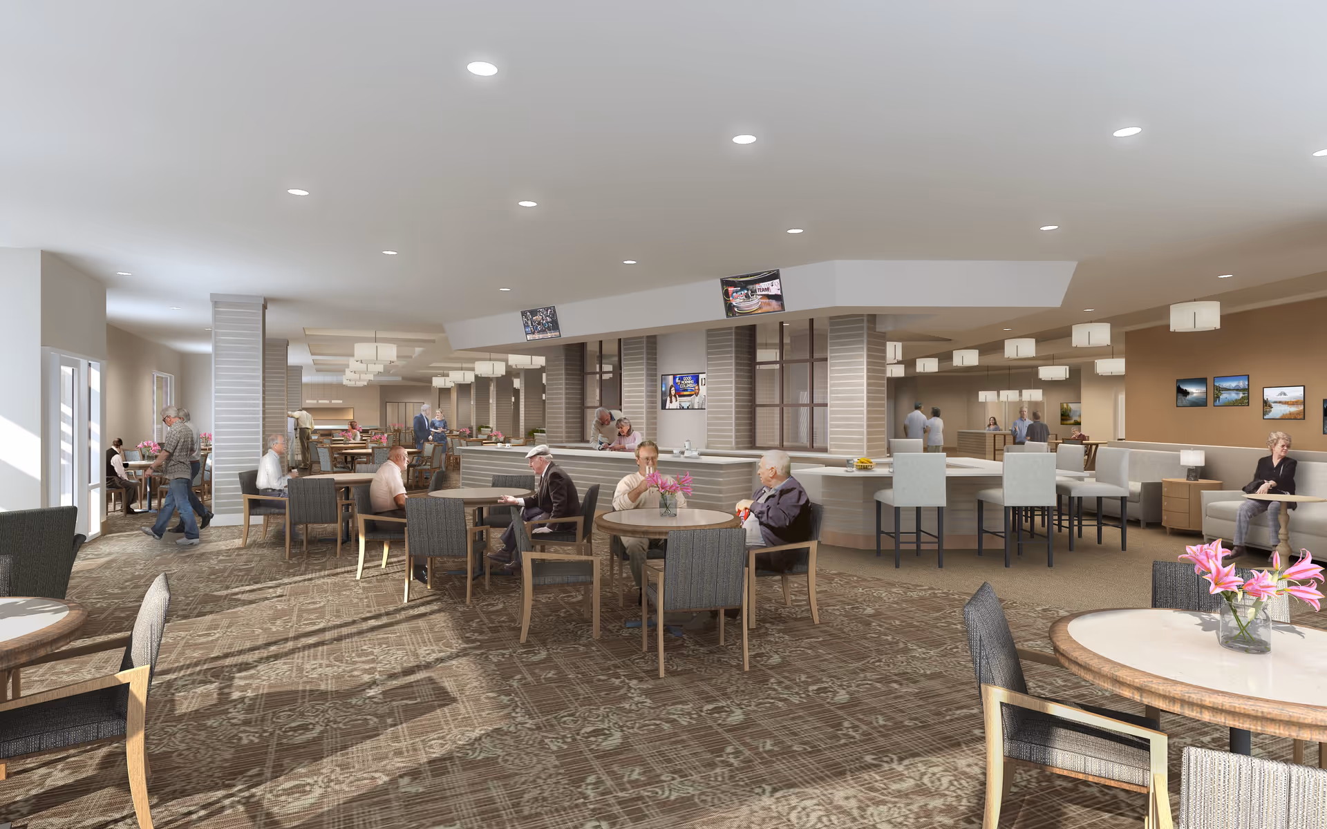 A spacious dining room in a senior living facility with multiple round tables and chairs. Several elderly residents are seated and engaged in conversation or activities. The room is well-lit with recessed ceiling lights and large windows allowing natural light. There is a counter area with high chairs and a few flat-screen TVs mounted above. The walls are decorated with framed pictures, and there are flower vases on some tables.