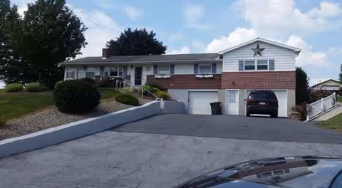 Exterior of a low brick building with a star on the front and a driveway.