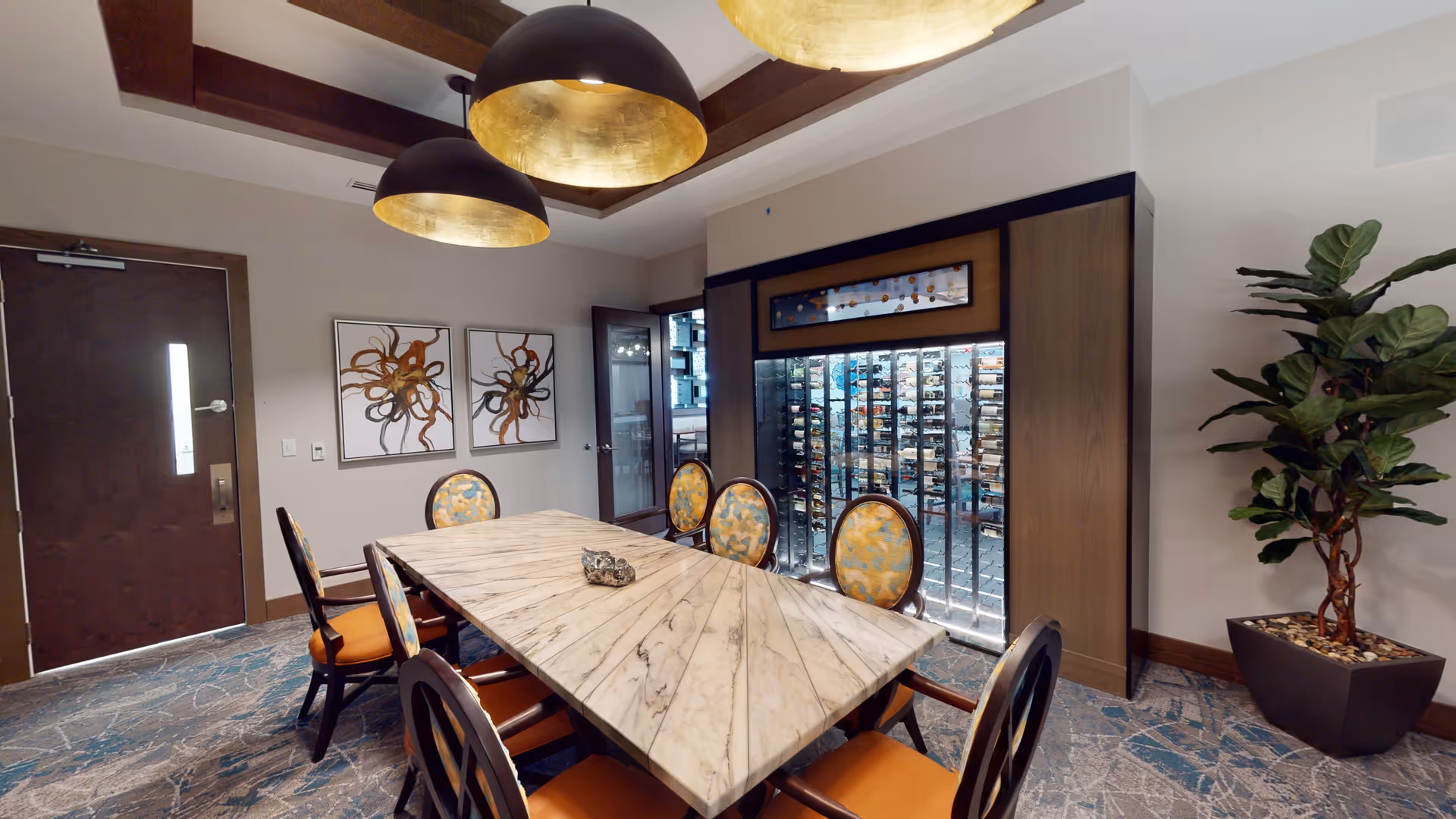 Private dining room with a long marble table, upholstered chairs, pendant lights, and a glass-enclosed wine display.