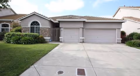 Front view of a two-car garage home with manicured lawn and driveway.