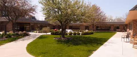 Exterior of Courtyard Healthcare Center with a landscaped courtyard, walkway, and seating.
