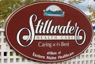 Oval Stillwater Health Care sign mounted on a lattice fence in front of a building.