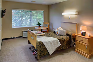 A furnished bedroom with an adjustable bed, nightstands, lamp, plant, and window.
