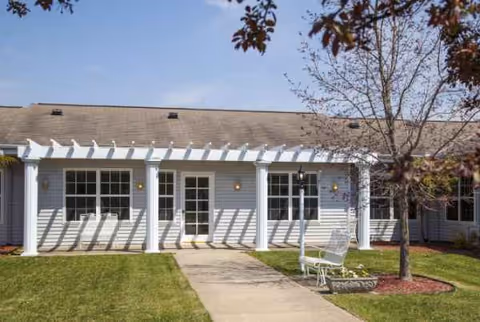 White, single-story senior living facility exterior with a columned porch and lawn.