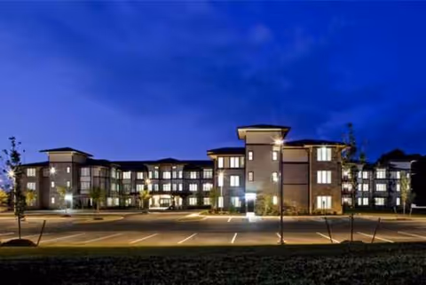 Exterior night view of Waterside Villas showing a multi-wing senior living building and parking lot.