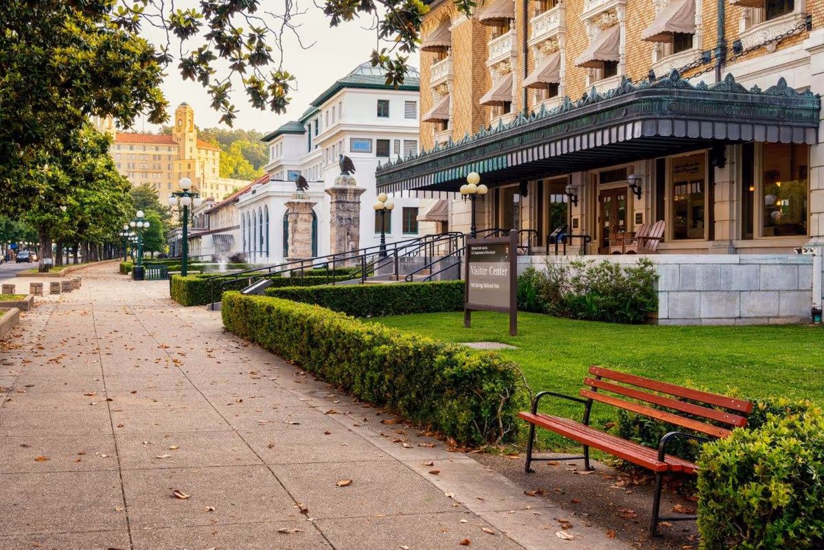 Exterior view of a senior living facility with walkway, benches, and manicured lawn