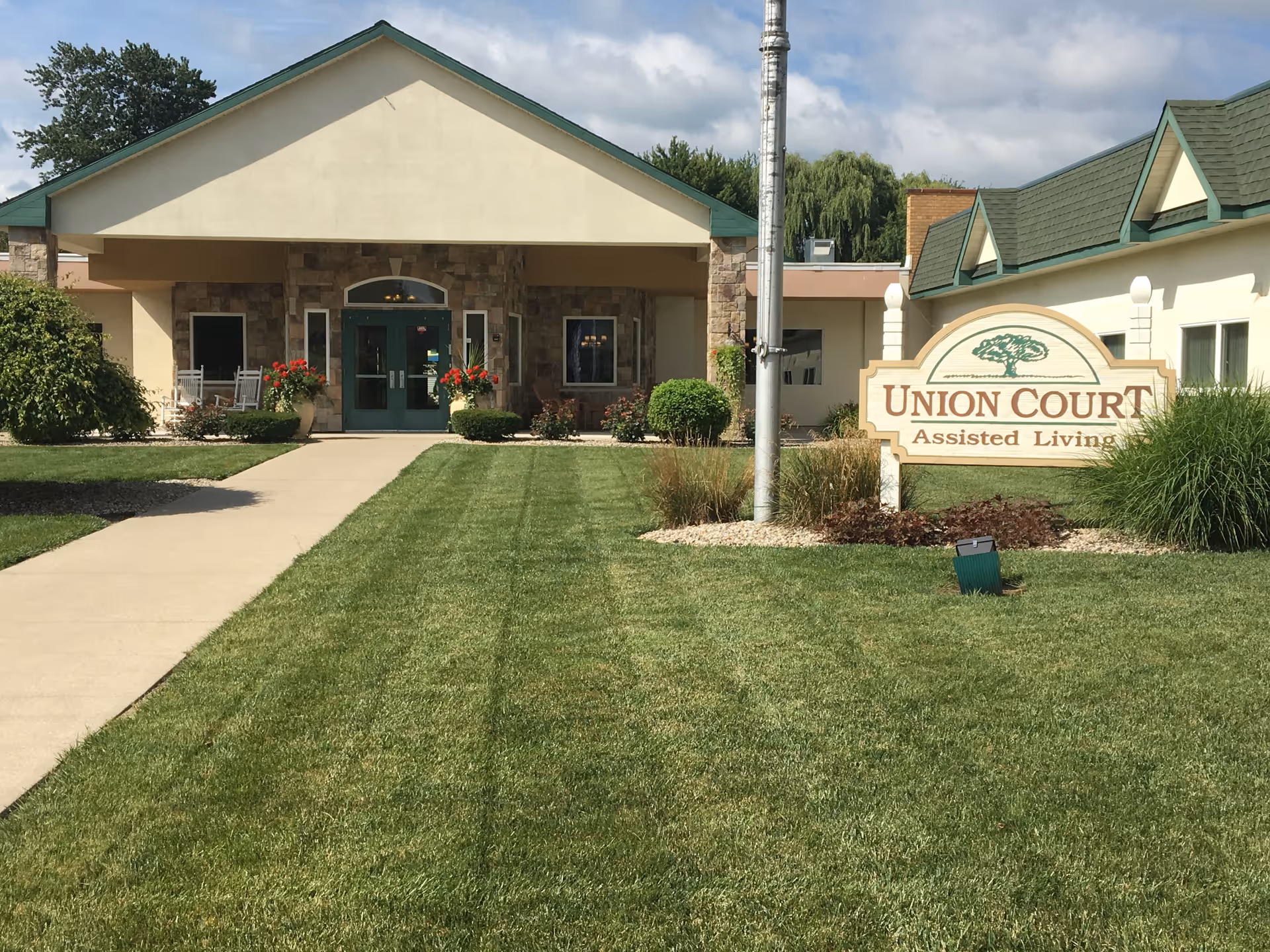 Front entrance of the Union Court Assisted Living building with a sidewalk, manicured lawn, and a large sign.