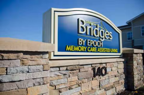 Front exterior sign reading Bridges by Epoch Memory Care Assisted Living mounted on a stone wall.