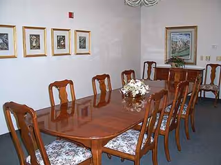 A long wooden dining table with chairs arranged in a formal dining room.