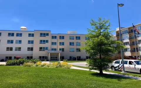 Gateway Vista senior living building visible with lawn, trees, and parked car in front.