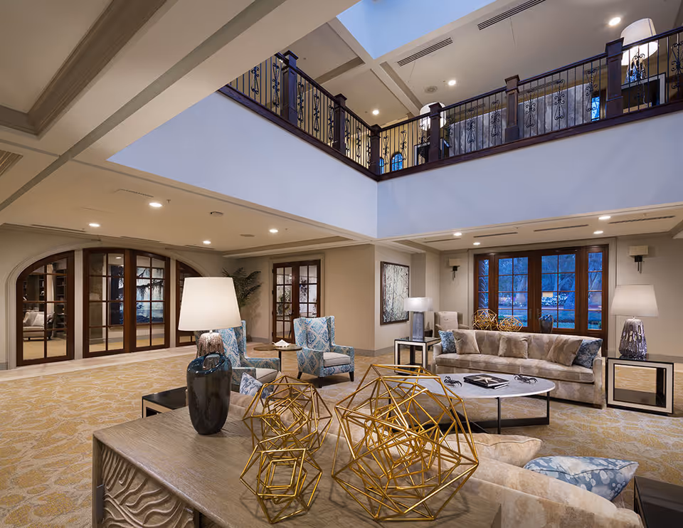 Spacious two-story lounge with sofas, armchairs, decorative tables and a second-floor railing overlooking the seating area.
