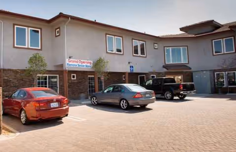 Exterior view of Ramona Senior Manor with cars parked in front.