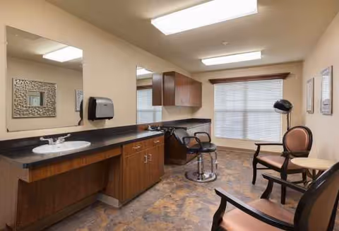 A senior living facility hair salon with mirrors, sinks, cabinets, styling chairs, and a window.