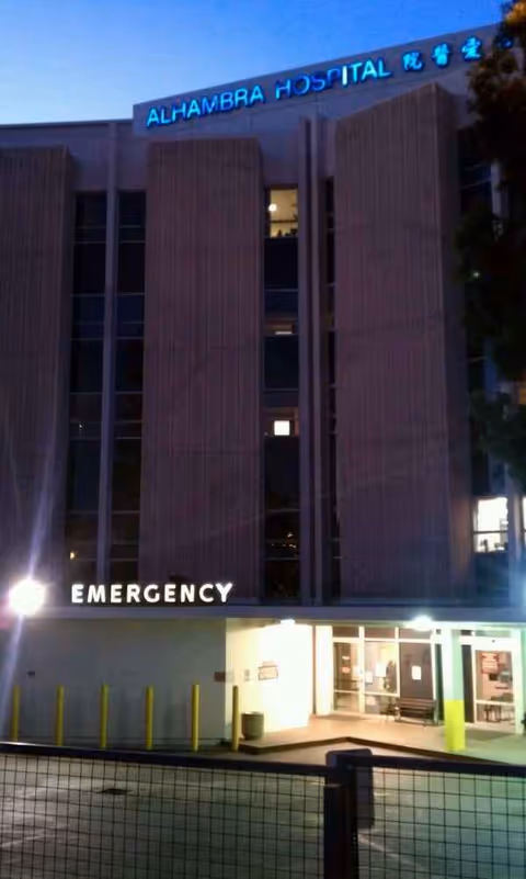 Nighttime exterior view of Alhambra Hospital Medical Center with illuminated emergency entrance