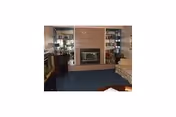 Cozy living room with fireplace, built-in shelves, and seating in a senior care facility.