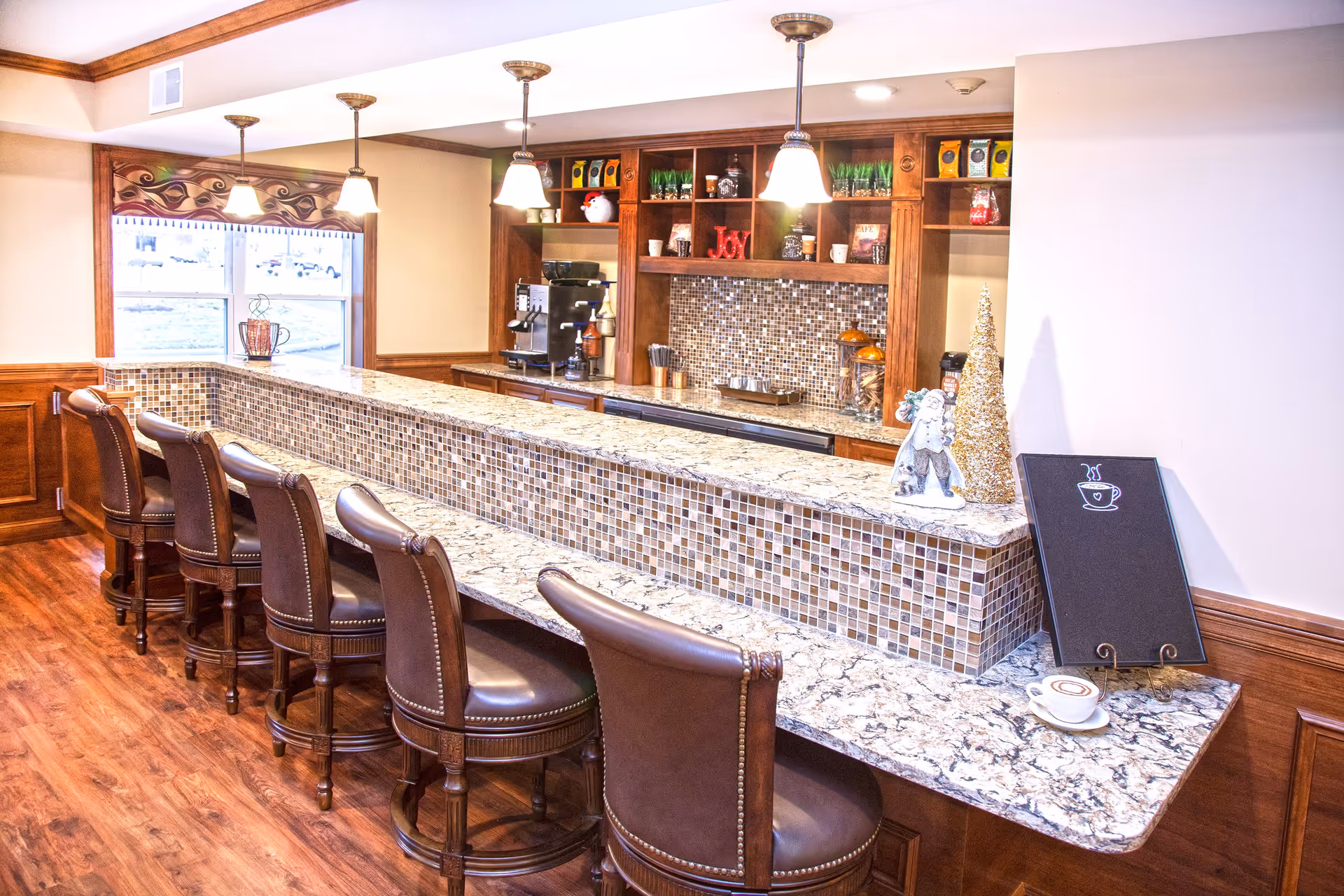 Interior coffee bar with marble countertop, mosaic tile front, pendant lights and leather bar stools.